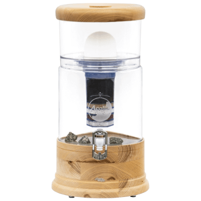 AcalaQuell Wasserfilteranlage mit transparentem Behälter und Holzelementen, die auf natürliche Wasseraufbereitung hinweist.